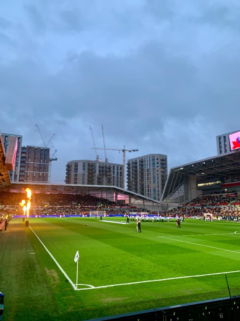 Football stadium corner with pyrotechnics and packed stands at dusk