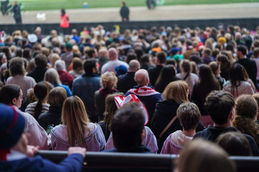 Crowd of supporters seated in a stadium, seen from behind